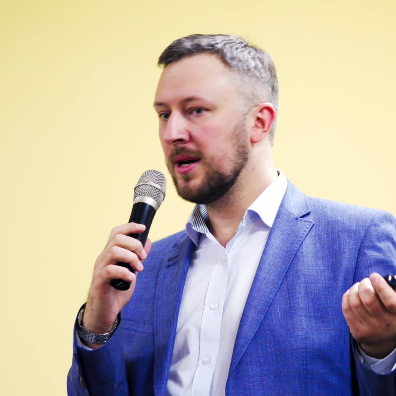 Professional businessman in blue suit talking into the microphone in conference hall. Handsome man speaker conducting a lecture on business forum.