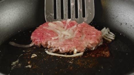 cooking a hamburger patty in a pan