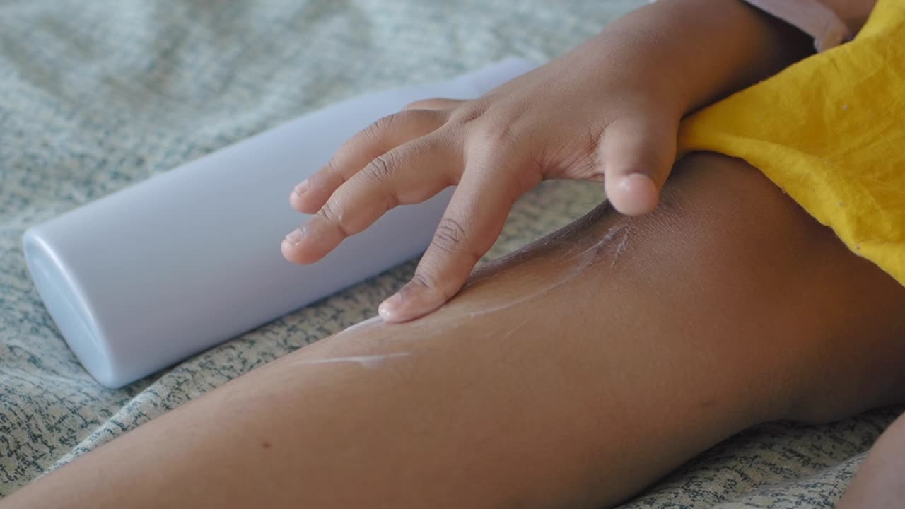 Bambino che applica la lozione sulla gamba