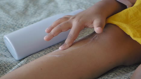 child applying lotion to leg