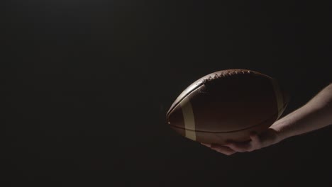 close up studio shot of american football player holding ball with low key lighting 5