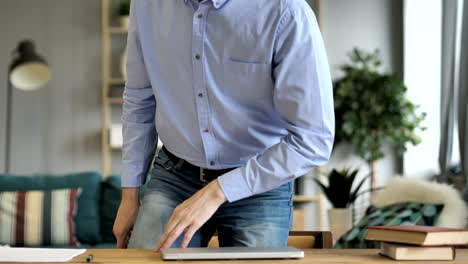 casual businessman closing laptop, standing and leaving workplace