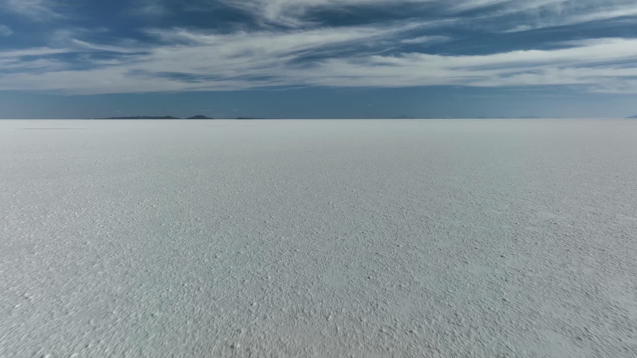 Uyuni, Bolivia - Teman-teman wisatawan berlari bebas sendirian di Salar de Uyuni yang gurun, tertutup air dan garam, dalam gerakan lambat yang romantis