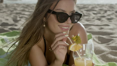 close-up shot of happy woman drinking cocktail on sandy beach