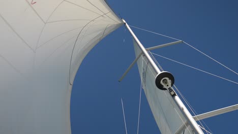 hand-held shot of the wind being caught in the sailboat's sails on a bright sunny day