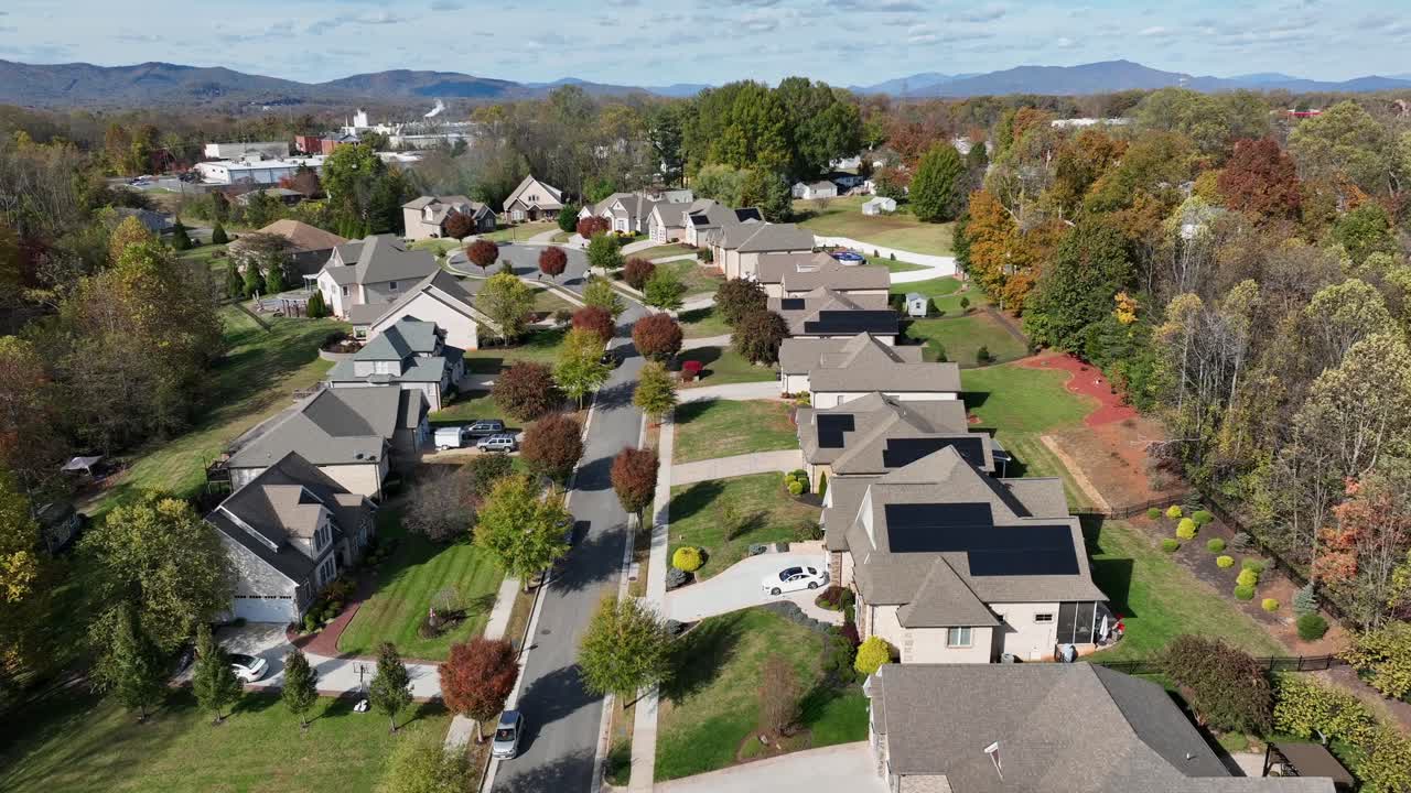 American modern suburb with neat homes, tree-lined streets, solar panels on rooftops and autumn colors in quiet residential neighborhood in bright daylight. aerial rising wide shot. Virginia, USA