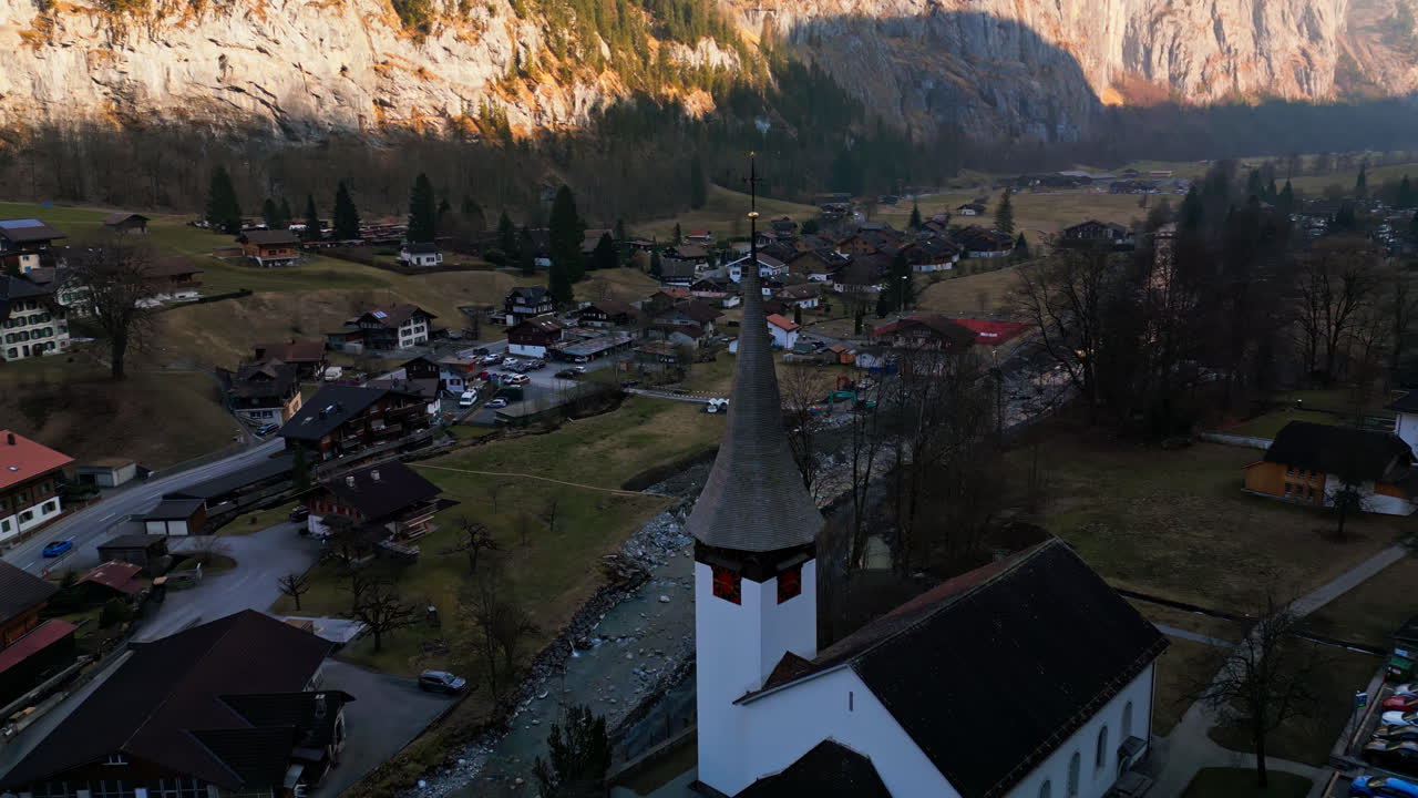 el avión no tripulado se retira de la aguja de la capilla para revelar la serena ciudad de lauterbrunnen, suiza en lo profundo del cañón