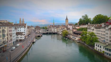 zurich switzerland aerial pull back up establishing shot church europe water river stream statue bridge europe steeple walkway people urban architecture 4k 60 fps tourist destination view swiss town