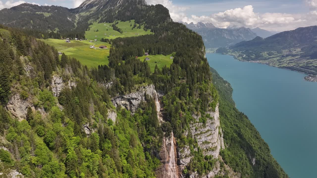waterfall flows from alpine meadows into lake walensee cliffs below