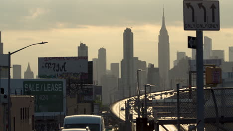 empire state building and midtown manhattan nyc skyline with traffic moving on long island expressway