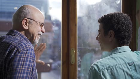 el abuelo anciano y el nieto charlan felizmente frente a la ventana.