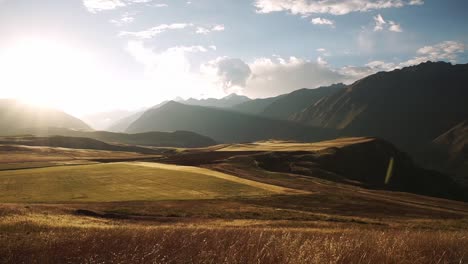 Sunrise-over-the-picturesque-sacred-valley-glowing-the-dried-grass-to-golden-and-lighting-up-the-whole-valley-with-light-rays,-chincheros,-cusco