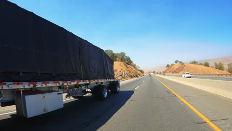 passing a bright blue freightliner truck while going up a slope on a highway in slow motion