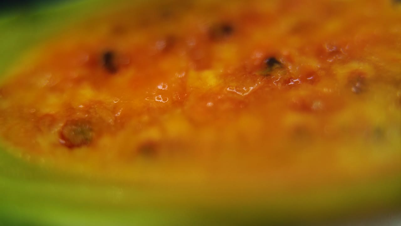 video macro detallado de una sabra en rodajas, fruta de cactus tropical naranja abierta con semillas, movimiento de retroceso suave, movimiento lento 120 fps
