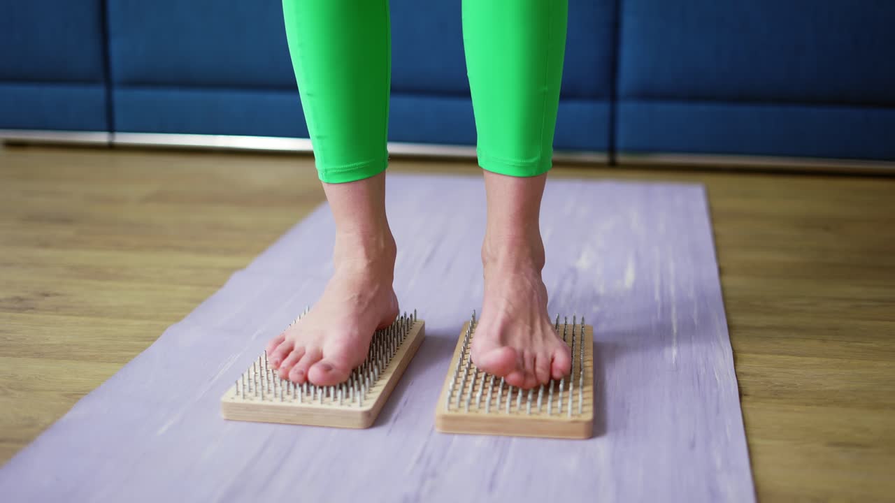Close up of woman's feet standing on sadhu board indoors at home