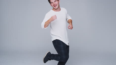 Wide-Angle-Studio-Shot-Of-Young-Man-Against-White-Background-Dancing-In-Slow-Motion