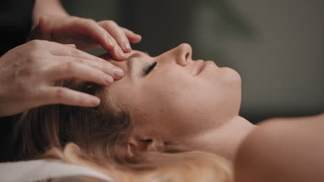 chiropractor is massaging acupuncture points on face of woman for relaxing and curing headache