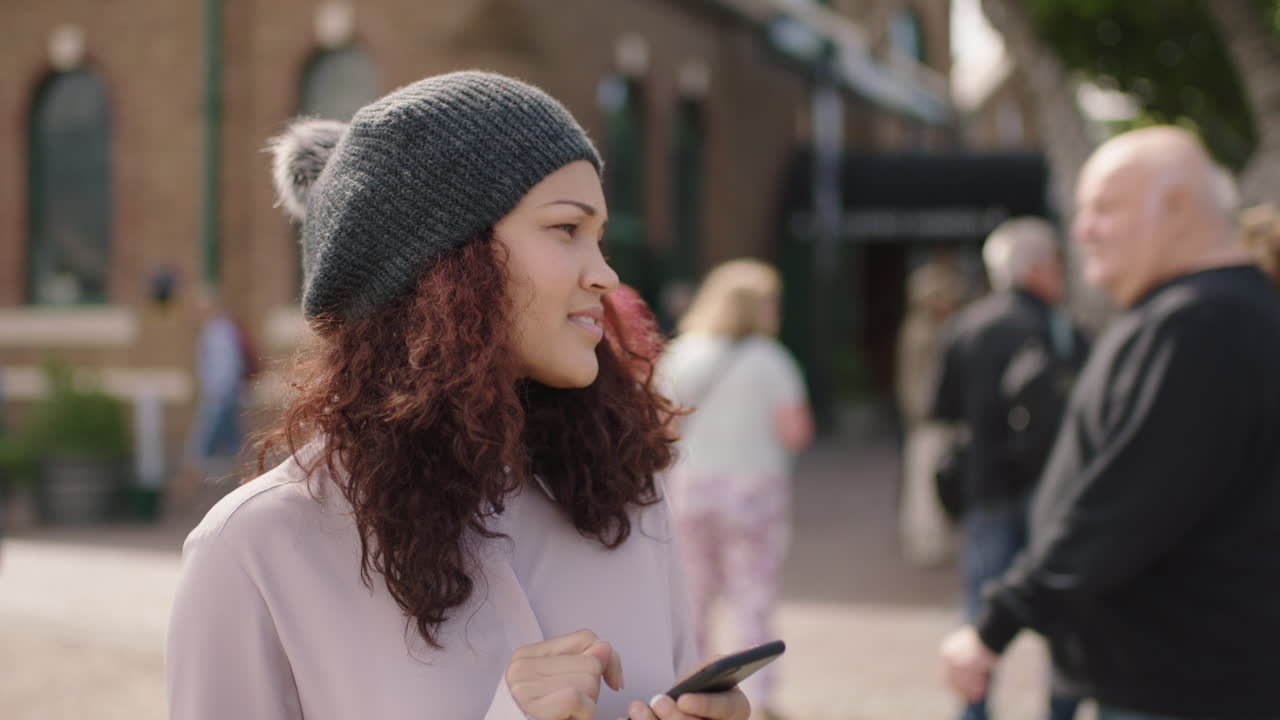 스마트 폰을 사용하여 도시 거리에서 기다리는 젊은 예쁜 여성의 초상화