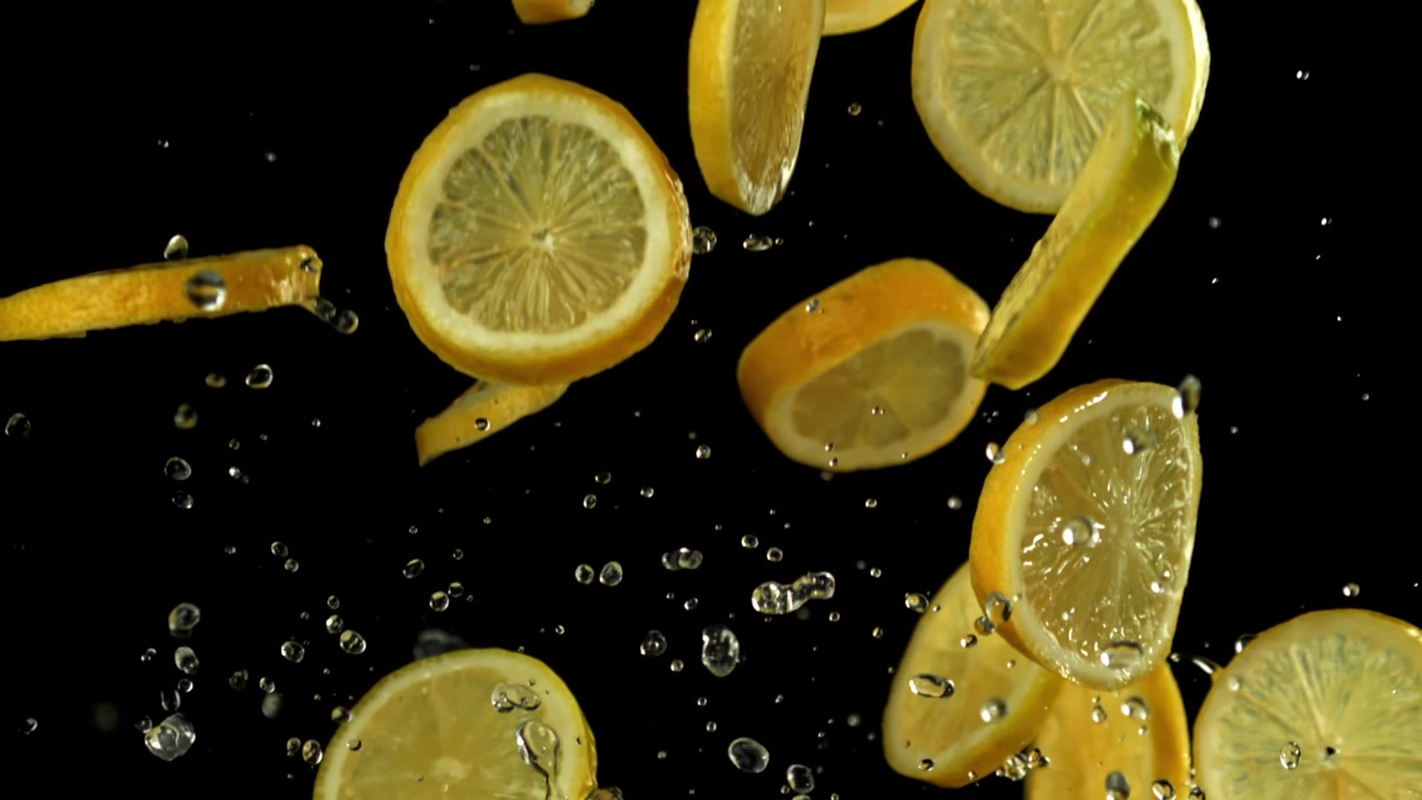 Fette di limone fresche e gocce d'acqua che cadono al rallentatore