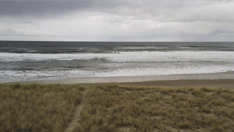 Aerial-View-Over-Sandy-Wild-Beach-Towards-Ocean-With-Cloudy-Sky-In-Background,-Neskowin-Oregon-Coast