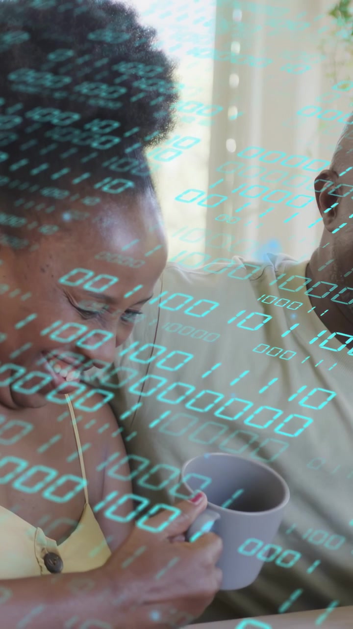 Vertical video: Couple sharing laugh while woman lifting mug, cyan binary code showing tech warmth