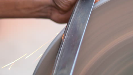 hands of construction worker sharpens a knife on sanding machine