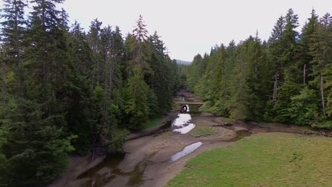 Waldbach-Mit-Holzbrücke,-Ruhige-Luftschwenkaufnahme-Im-Sandkasten,-Kanada