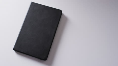 close up of closed black book with copy space on white background in slow motion