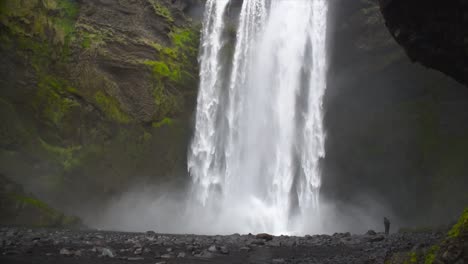 man at the base of large waterfall