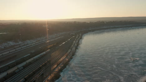 Aerial-shot-of-park-by-lake-at-sunset