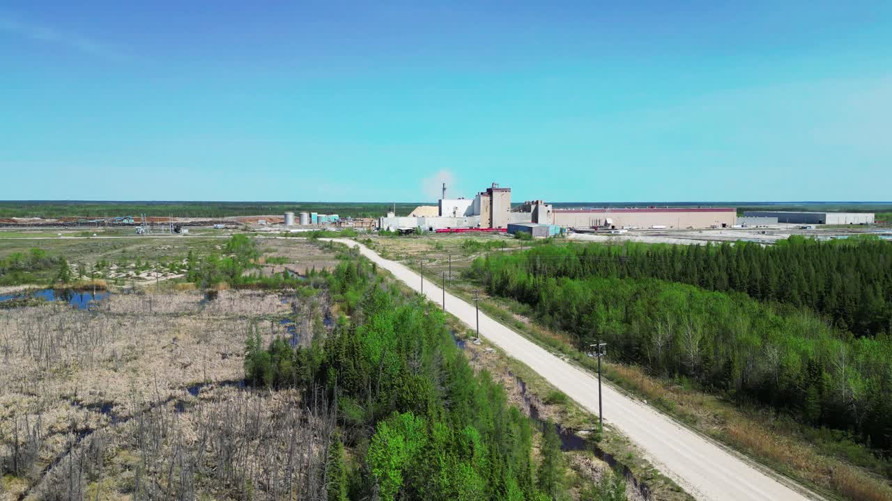 An aerial moving view of the Canadian Kraft Paper and Pulp Mill outside The Pas, Manitoba, Canada from the Umpherville Access road during the daytime in the Summer of 2025.
