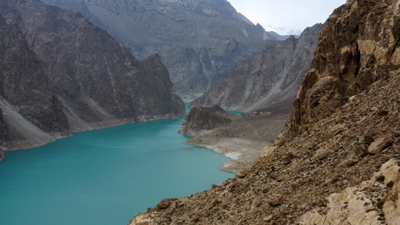 lago tranquilo rodeado de montañas rocosas en el lago attabad, valle de gojal, hunza, gilgit-baltistán, pakistán