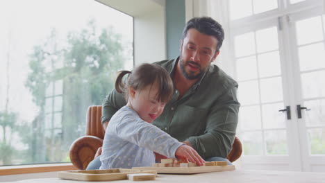 Padre-Con-Hija-Con-Síndrome-De-Down-Jugando-Con-Formas-De-Madera-En-Casa-Juntos