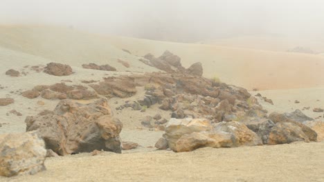 vista de enormes piedras pómez en la arena amarillenta en el nebuloso parque nacional de teide