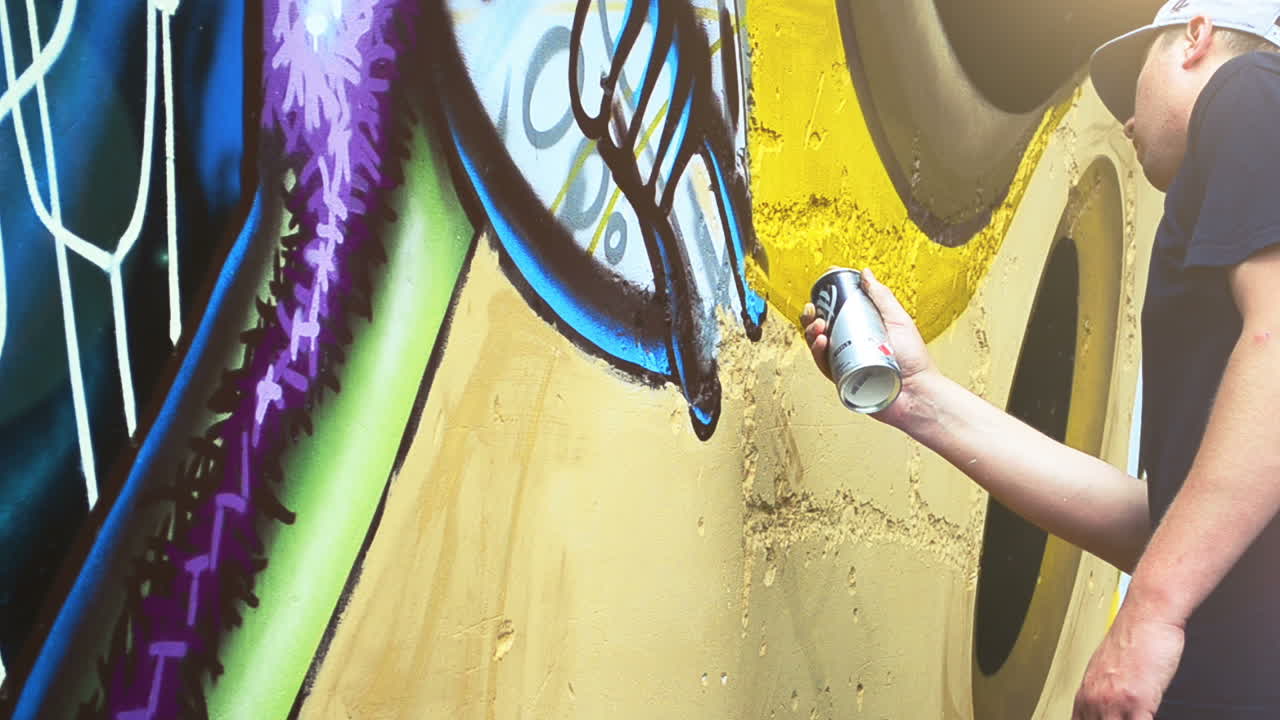De kunstenaar spuit graffiti op een hek. Abstracte tekening