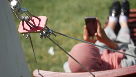 woman relaxing in a hammock and using her phone