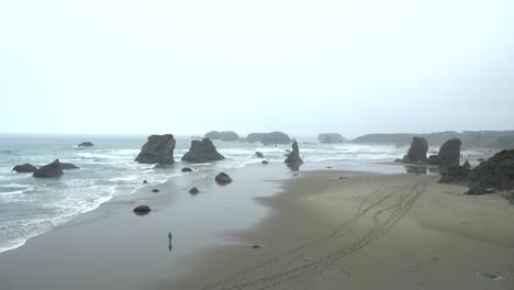 Person-walking-on-a-beach-in-Oregon-coast-on-a-rainy-day