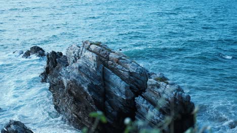 Spectacular-clash-of-azure-waves-against-the-rocky-shore-of-Mexico,-framed-by-tranquil-greenery,-embodying-a-serene-yet-dynamic-coastal-tableau