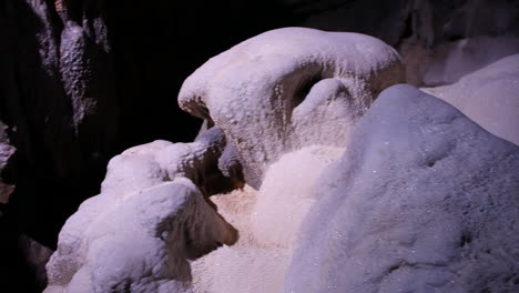 white mineral formations from deposits in a cave underground, glistening under dim lighting