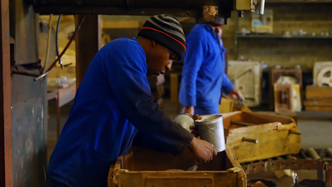 Male worker painting metal casting in workshop 4k