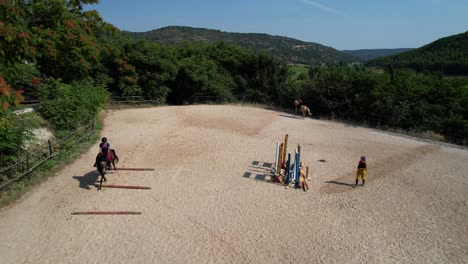 pullback aerial view shows a trainer observing as a rider practices jumping between three ground bars