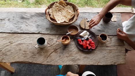 social communication in dining table in morning breakfast time with wooden table, basket, flat bread, jam, tomato, cheese, tea, coffee drink