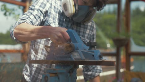 young caucasian man planing teak wood timber with electrical planer