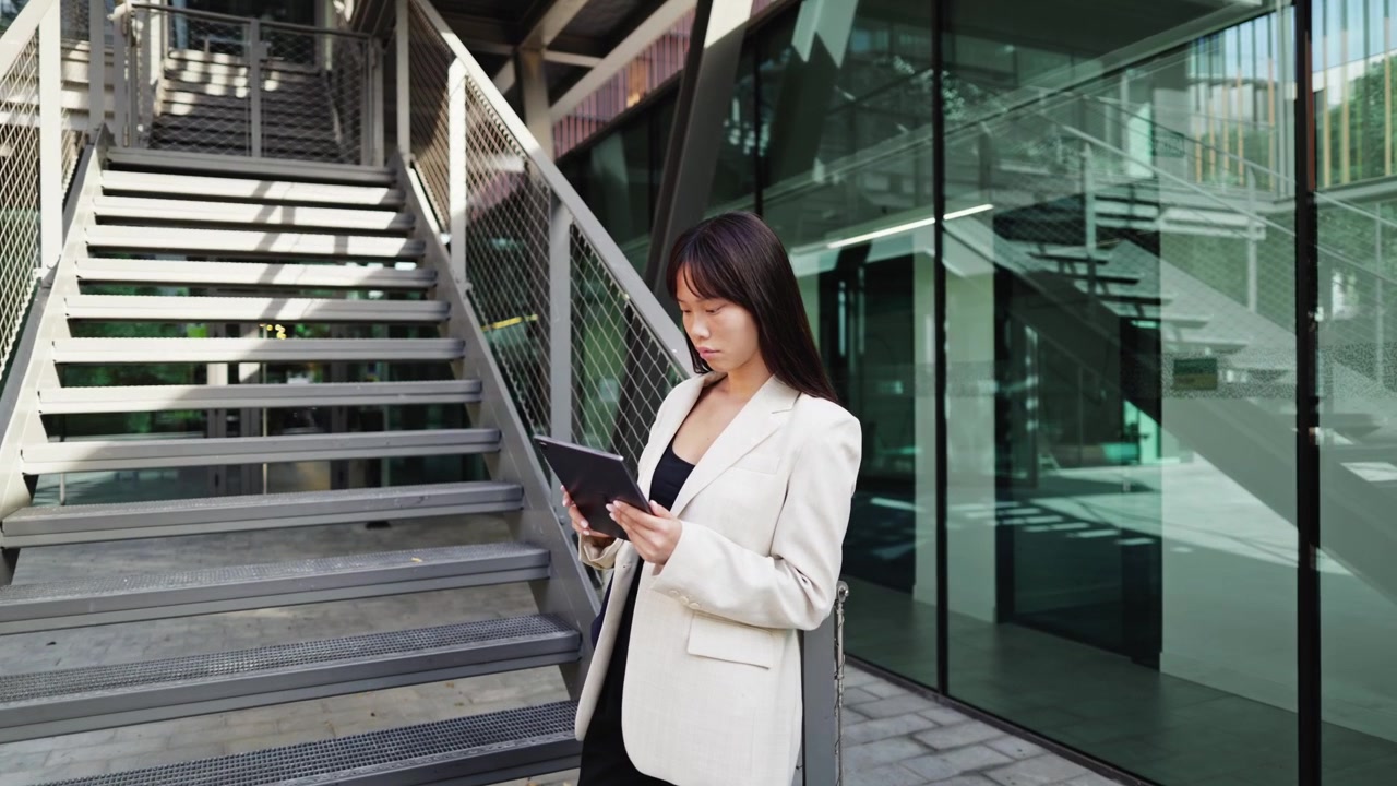 企業ビルの外でタブレットに集中して作業するビジネスウーマン