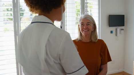 Female-Nurse-Wearing-Uniform-Listening-To-Senior-Female-Patient's-Chest-In-Private-Hospital-Room