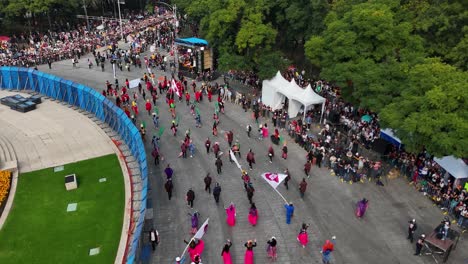 aerial shot of participants in the day of the dead parade with colorful banners over paseo de la reforma in mexico city