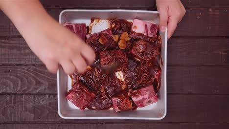 marinando costillas de carne cruda con salsa en un molde para hornear