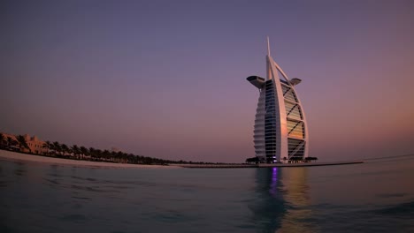 scenic view of the burj al arab, a luxury hotel located in dubai, united arab emirates, reflecting on the calm sea during a breathtaking sunset, creating a tranquil and picturesque scene