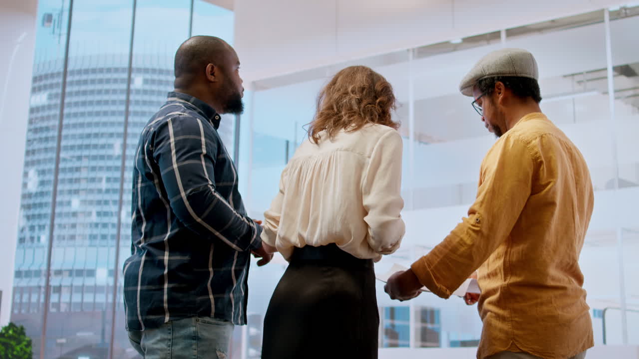 Real estate agent guiding clients on office hunt with layout blueprints