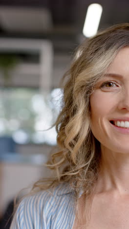 vertical video of half portrait of happy caucasian casual businesswoman in office, slow motion